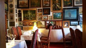 Gastraum mit edel gedeckten Tischen und französischer Bestuhlung vor einer großen Gemäldewand